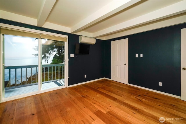 585 Raccoon Point Rd, Orcas Island, WA 98245 - empty room with a wall mounted AC, beam ceiling, baseboards, and hardwood / wood-style flooring