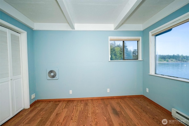 585 Raccoon Point Rd, Orcas Island, WA 98245 - unfurnished bedroom featuring a baseboard heating unit, beamed ceiling, wood finished floors, a closet, and baseboards