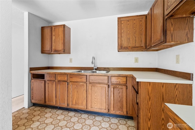 kitchen with a sink, brown cabinetry, and light countertops