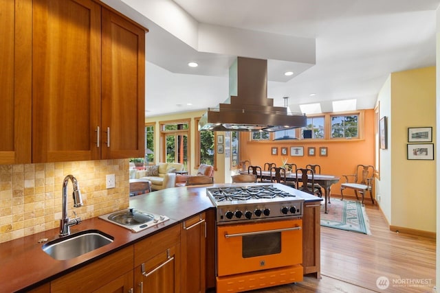 1433 Madison St, Port Townsend, WA 98368 - kitchen featuring a sink, range with gas stovetop, island exhaust hood, tasteful backsplash, and light wood-style flooring