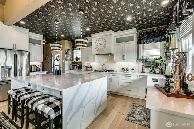 1774 Farmview Ter, Lynden, WA 98264 - kitchen with appliances with stainless steel finishes, white cabinetry, a center island, glass insert cabinets, and light wood-style floors
