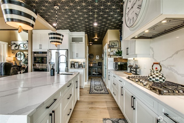 1774 Farmview Ter, Lynden, WA 98264 - kitchen featuring appliances with stainless steel finishes, custom range hood, a sink, light wood finished floors, and white cabinetry