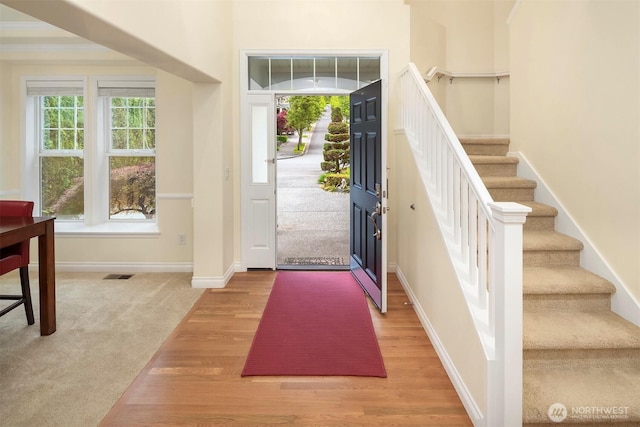 foyer entrance with stairs, light wood-style floors, and baseboards