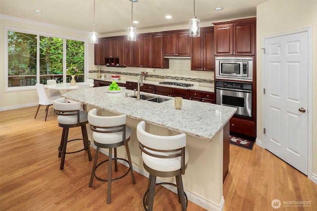 kitchen with stainless steel appliances, a sink, decorative backsplash, light wood-style flooring, and recessed lighting