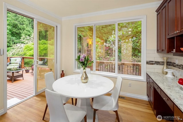 dining space featuring plenty of natural light, light wood-type flooring, ornamental molding, and baseboards