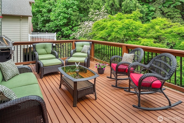 wooden terrace with an outdoor living space and area for grilling