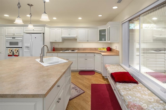 kitchen featuring white appliances, a sink, white cabinetry, light wood-style floors, and recessed lighting