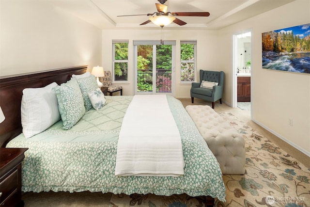 bedroom with a raised ceiling, ensuite bathroom, ceiling fan, and baseboards