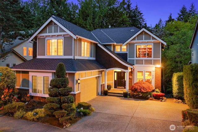 craftsman-style house featuring a shingled roof, driveway, and brick siding