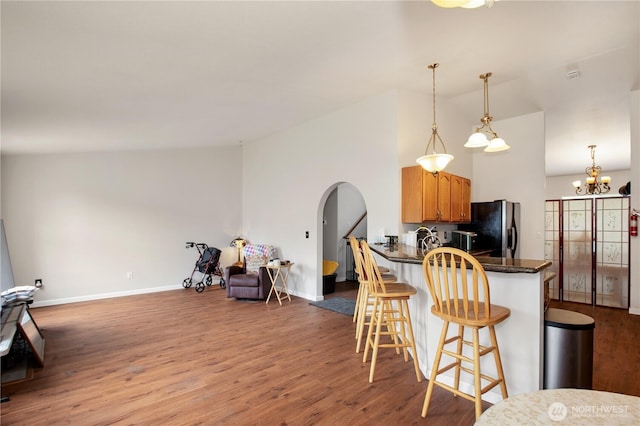 1431 Chatham Dr SE, Olympia, WA 98513 - kitchen featuring lofted ceiling, arched walkways, freestanding refrigerator, dark countertops, and wood finished floors