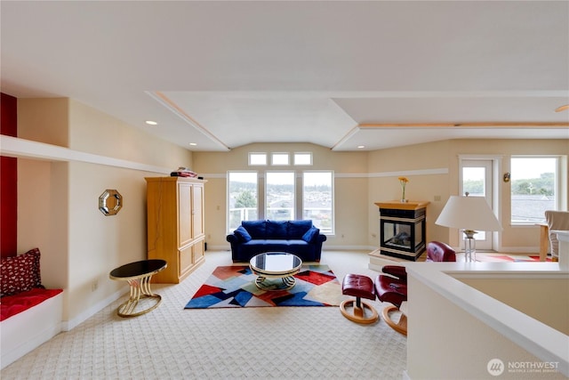 carpeted living room with healthy amount of natural light, a multi sided fireplace, lofted ceiling, baseboards, and recessed lighting