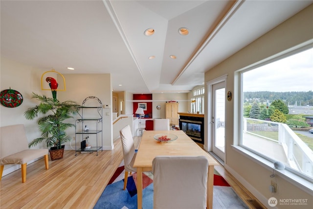 dining room featuring light wood finished floors, a multi sided fireplace, recessed lighting, and baseboards