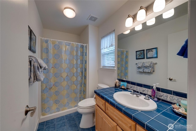bathroom with toilet, vanity, a shower with curtain, tile patterned floors, and baseboards