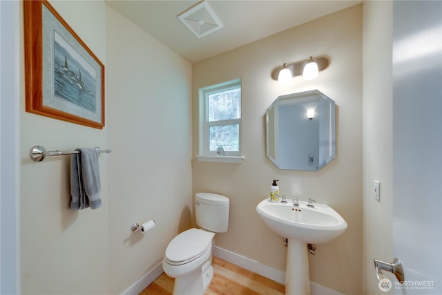 half bathroom with toilet, baseboards, and wood finished floors