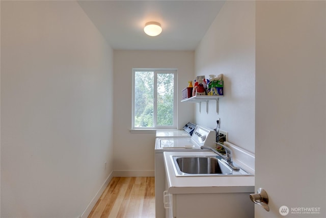 clothes washing area with washer and dryer, light wood-style floors, and baseboards