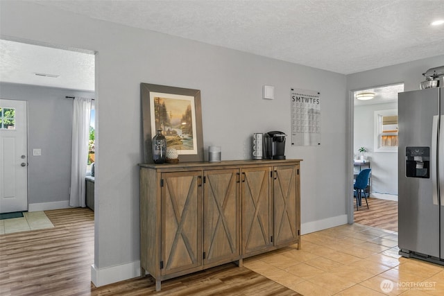 interior space with a textured ceiling, baseboards, and light wood-style flooring