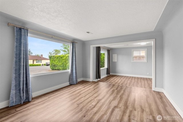 unfurnished room featuring wood finished floors, baseboards, and a textured ceiling