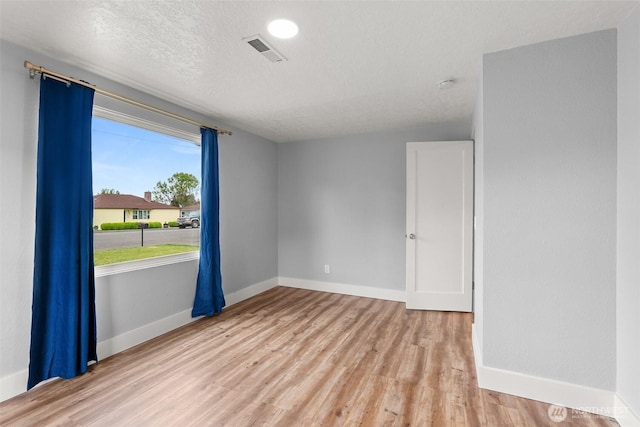 unfurnished room with wood finished floors, baseboards, a textured ceiling, and a smoke detector
