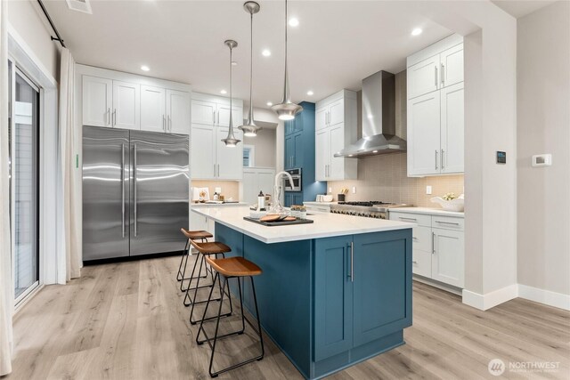 13213 164th Ave SE Unit 205, Renton, WA 98059 - kitchen featuring appliances with stainless steel finishes, wall chimney range hood, light wood-type flooring, tasteful backsplash, and light countertops