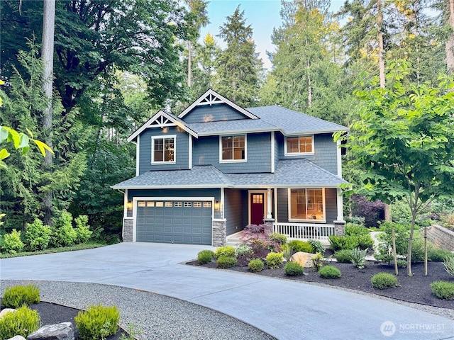 11626 Olympic View Dr NE, Bainbridge Island, WA 98110 - craftsman-style house featuring covered porch, an attached garage, driveway, stone siding, and roof with shingles