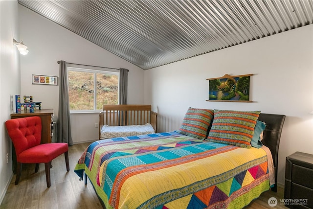 bedroom with vaulted ceiling, wood finished floors, and baseboards