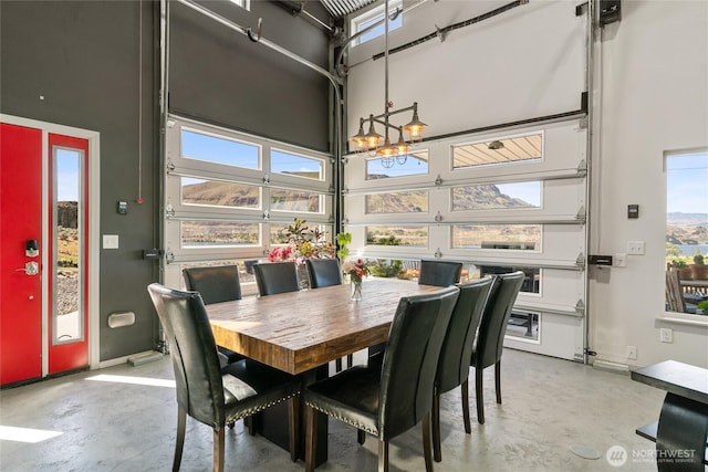 dining space featuring concrete floors, a high ceiling, and baseboards