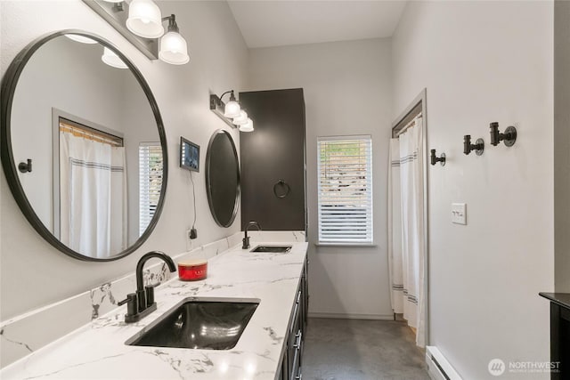 bathroom featuring concrete floors, double vanity, and baseboards