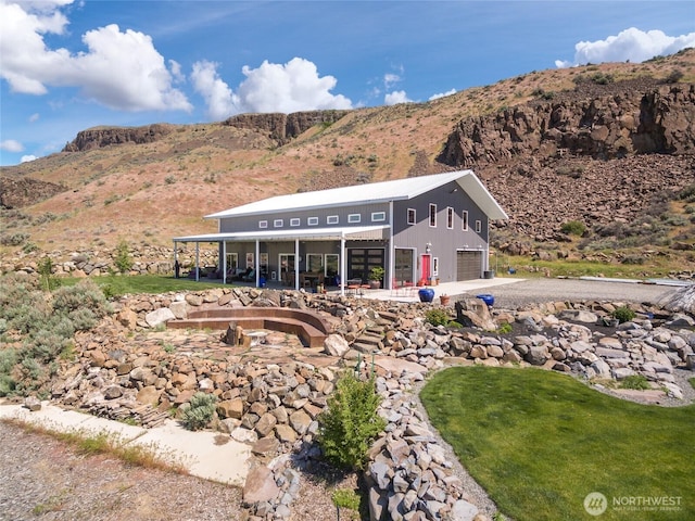 rear view of house featuring a mountain view, a garage, and driveway