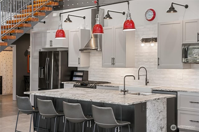kitchen featuring stainless steel appliances, decorative backsplash, an island with sink, and a breakfast bar area