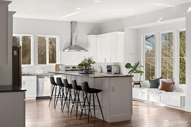 15403 127th Ave SE, Snohomish, WA 98290 - kitchen featuring wall chimney exhaust hood, stainless steel appliances, backsplash, dark stone countertops, and recessed lighting