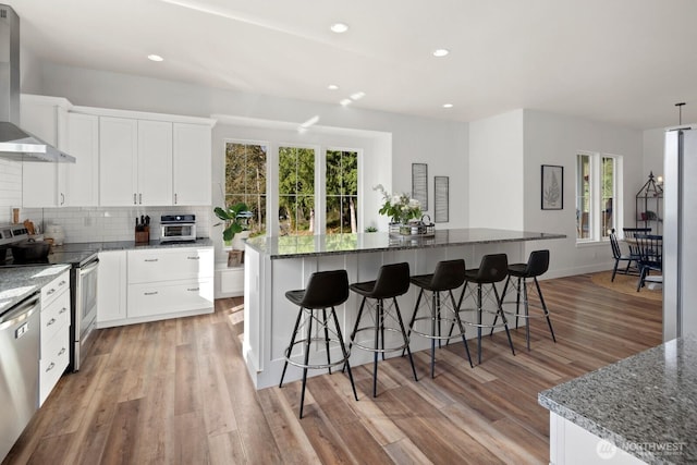 15403 127th Ave SE, Snohomish, WA 98290 - kitchen with wall chimney exhaust hood, stainless steel appliances, a center island, backsplash, and light wood-style floors