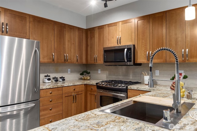 1840 25th Ave NE Unit 308, Issaquah, WA 98029 - kitchen featuring appliances with stainless steel finishes, brown cabinets, a sink, and tasteful backsplash
