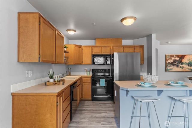 10307 140th Street Ct E Unit 4, Puyallup, WA 98374 - kitchen with black appliances, light countertops, a sink, and a breakfast bar area