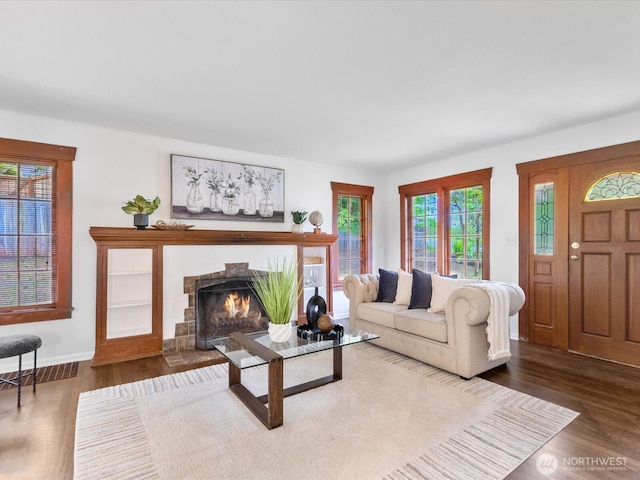 living room with wood finished floors, a warm lit fireplace, and baseboards