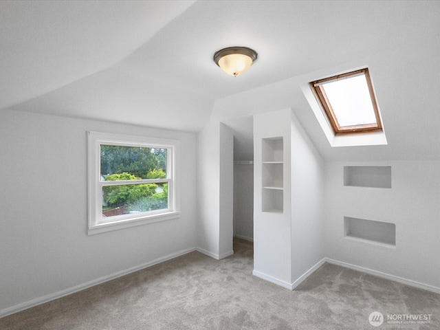 additional living space featuring a skylight, lofted ceiling, carpet, and baseboards