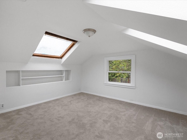 bonus room featuring a skylight, built in features, vaulted ceiling, carpet floors, and baseboards