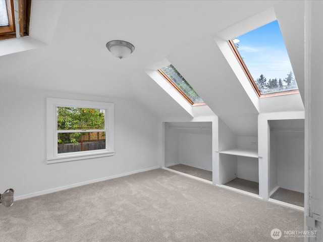 bonus room featuring a skylight, carpet flooring, and vaulted ceiling