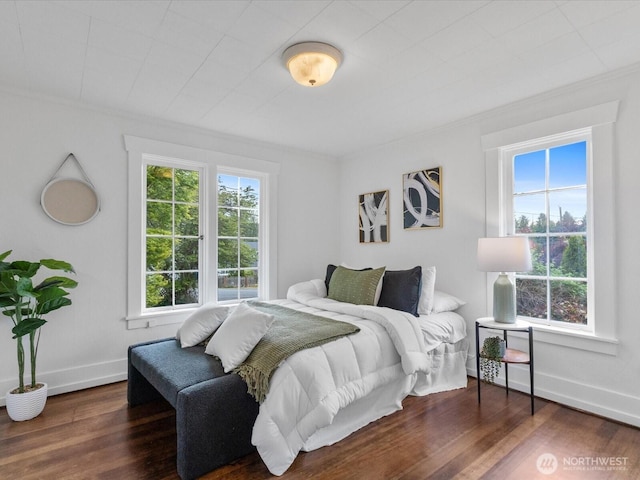 bedroom with multiple windows, wood finished floors, ornamental molding, and baseboards