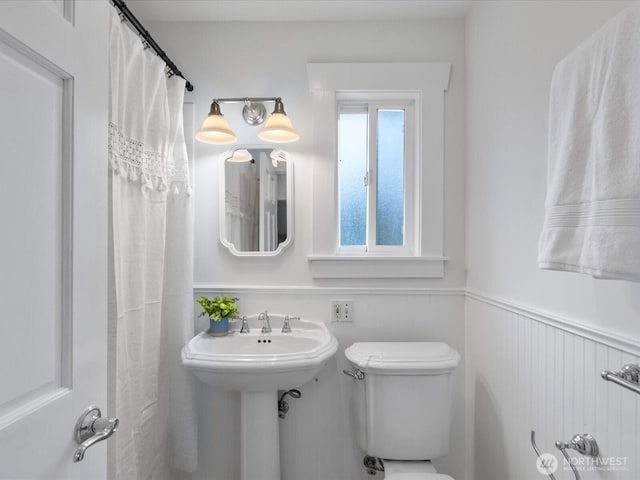 bathroom featuring toilet and wainscoting