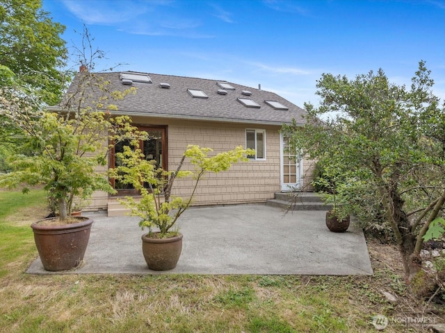 back of house featuring roof with shingles and a patio area