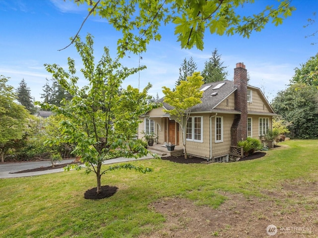 view of front of property featuring a front lawn, a chimney, and a shingled roof