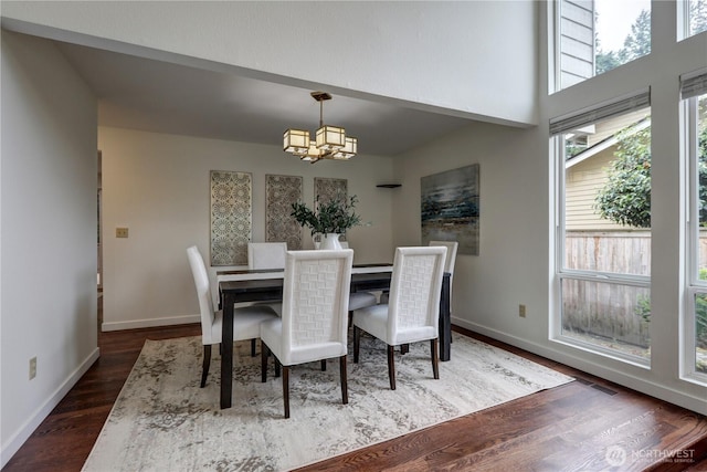 dining area with a chandelier, dark wood-type flooring, and baseboards