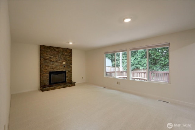 unfurnished living room with carpet flooring, a stone fireplace, and recessed lighting
