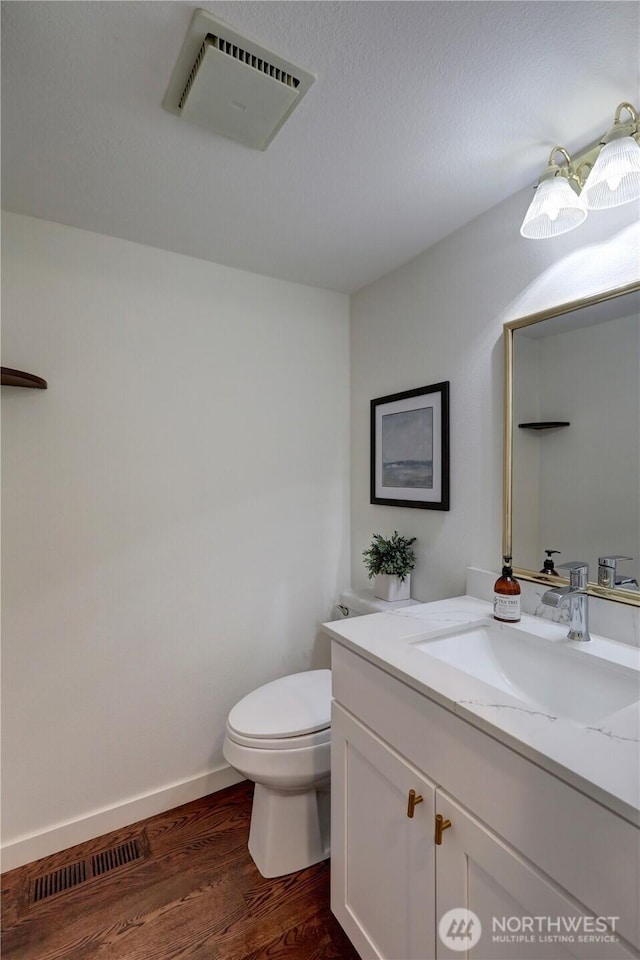 bathroom featuring toilet, vanity, wood finished floors, and baseboards