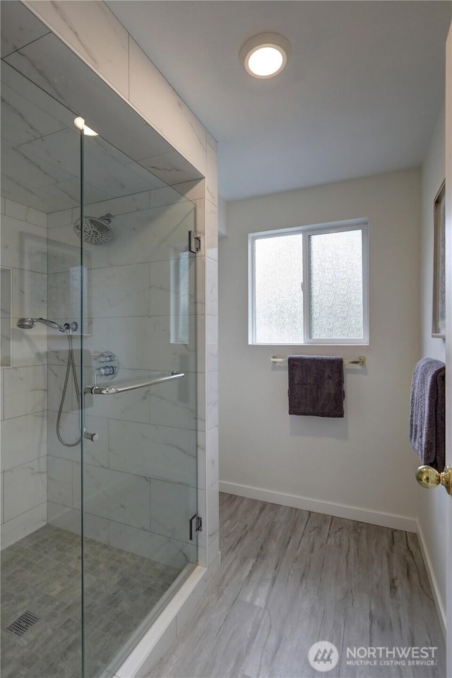 bathroom with a stall shower, baseboards, and wood finished floors