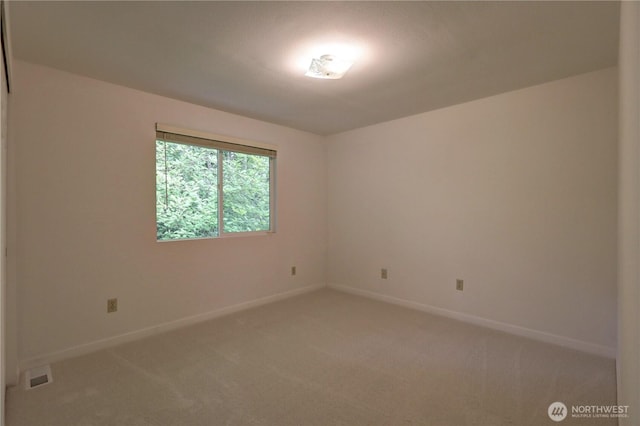 empty room featuring light carpet and baseboards