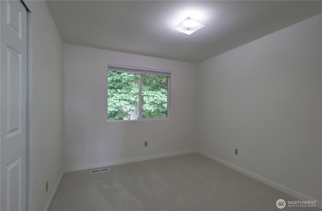 unfurnished room featuring light carpet and baseboards