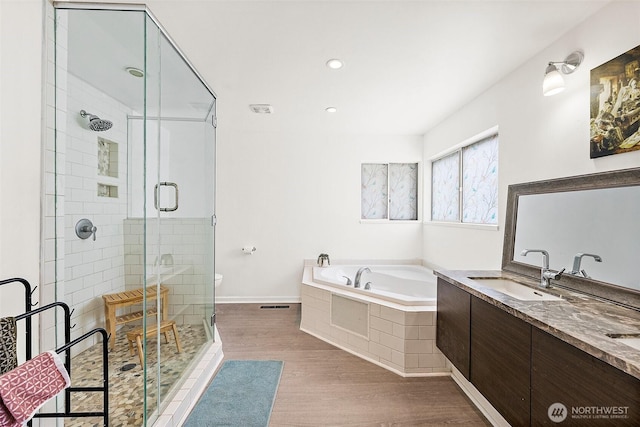 full bath with wood finished floors, a garden tub, a stall shower, double vanity, and recessed lighting