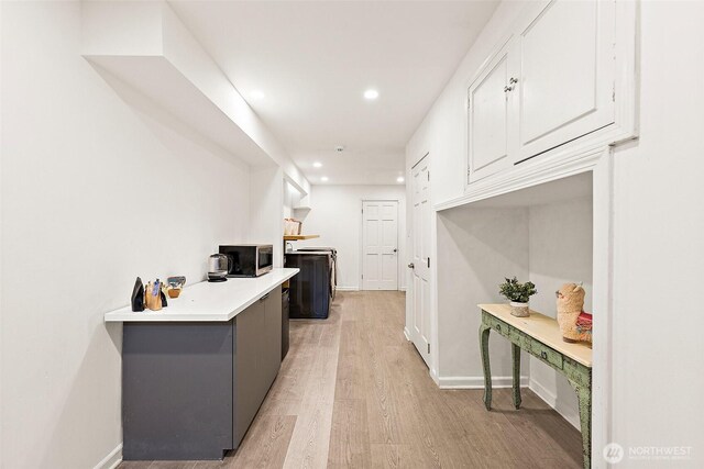 kitchen with stainless steel microwave, recessed lighting, white cabinetry, light wood-style floors, and light countertops