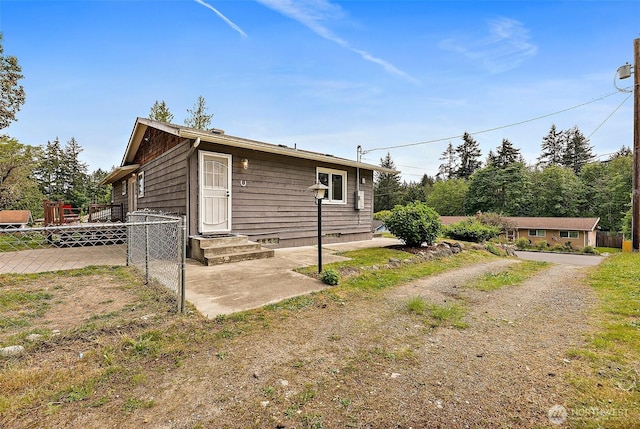 back of property featuring fence and dirt driveway